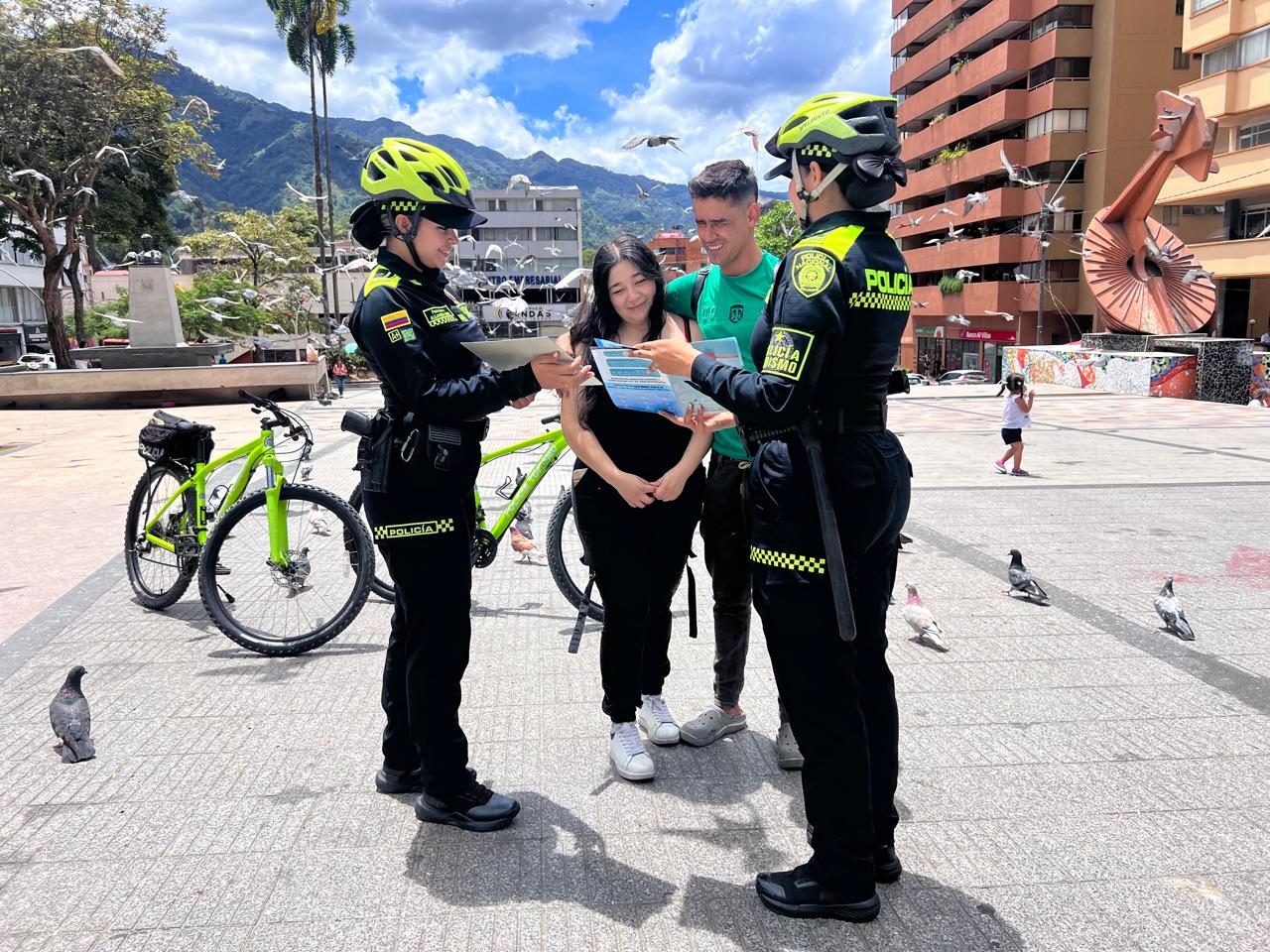 Dos polic&iacute;as de turismo dando indicaciones una mujer y un hombre en un parque