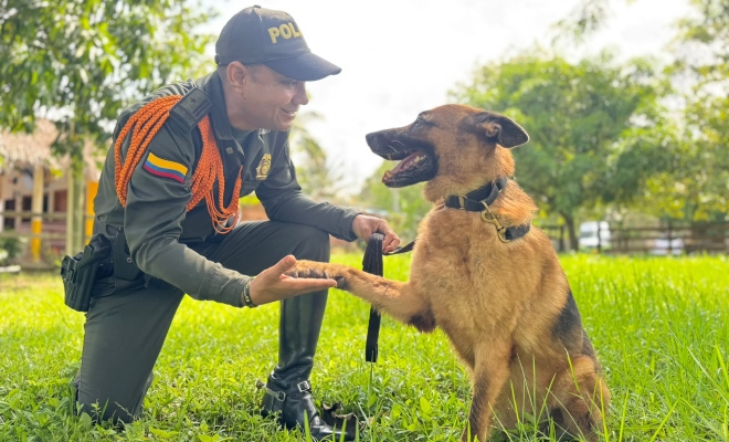 Funcionario policial dando la mano a un canino y sonriendo