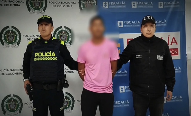Un funcionario de policía,  un detenido y a la izquierda un funcionario de CTI