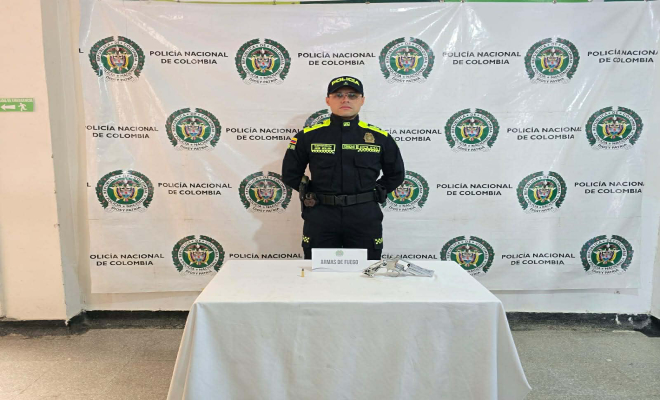 Policía detrás de una mesa con un revólver incautado. 