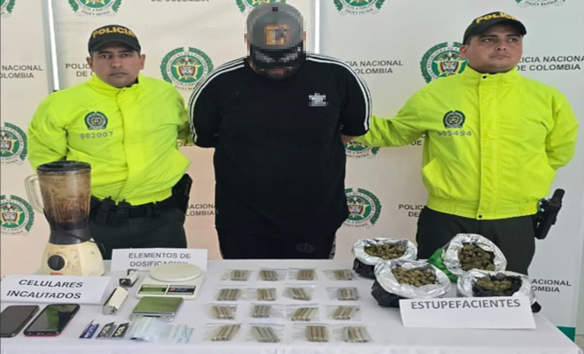 Se observa dos polic&iacute;as de la Sijin con un capturado y una mesa con marihuana , cigarrillo, dos celulares y elementos para dosificaci&oacute;n de alucin&oacute;genos