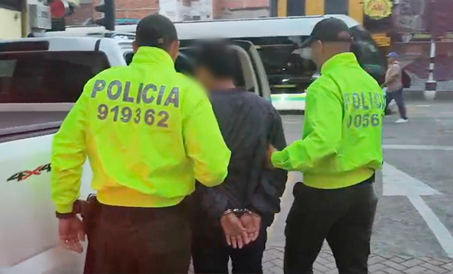 Dos policías llevan a un capturado para subirlo a una camioneta