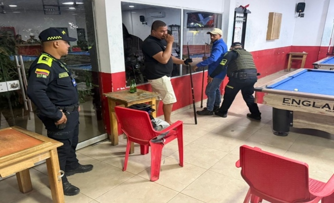 un policia registrando a dos ciudadanos y un policia prestando seguridad 