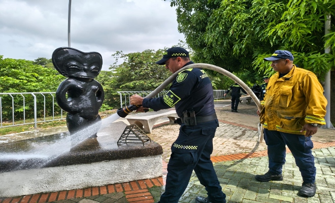 Un polic&iacute;a y un ciudadano realizando limpieza en el monumento 