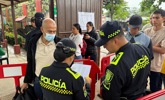 Dos policías en puesto de votación verificando ingreso de testigos electorales