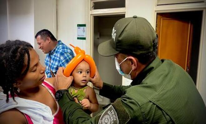 Policía entrega figura en globo a un menor acompañado de su familia.