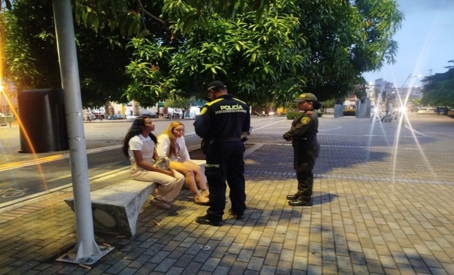 Dos polic&iacute;as realizando charla a dos ciudadanas 