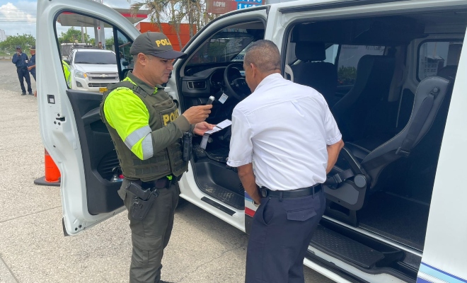 Funcionario policial de transito dando recomendaciones a un ciudadano junto a un vehículo 
