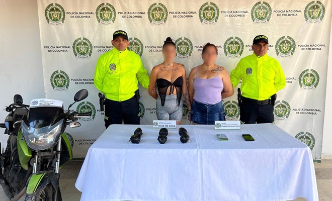 Se observan base de coca incautada sobre una mesa y una moto, dos mujeres capturadas