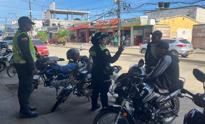 Funcionaria policial junto a un auxiliar de policía dando recomendaciones de seguridad a dos ciudadanos