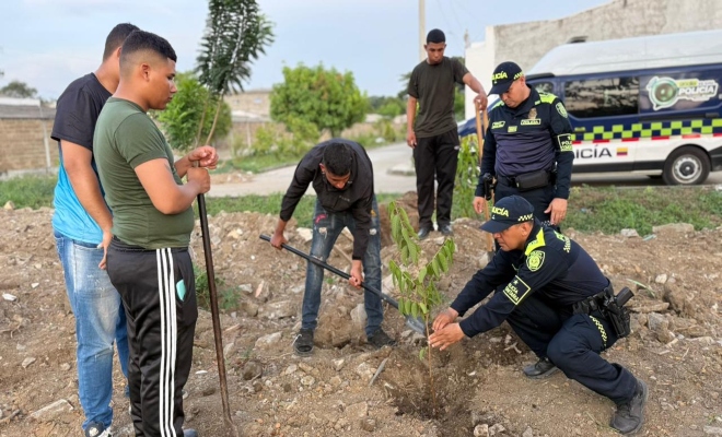 dos uniformados de la policía y cuatro ciudadanos organizando espacios y sembrando arboles fomentar el cuidado del medio ambiente mediante la recuperación y embellecimiento de las zonas comunes.
