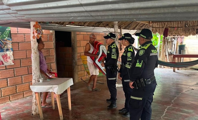 Tres funcionarios policiales realizando visitas puerta a puerta a dos ciudadanos