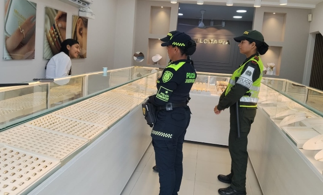 Tres funcionarios policiales brindando recomendaciones de seguridad a una ciudadana en sector comercial 