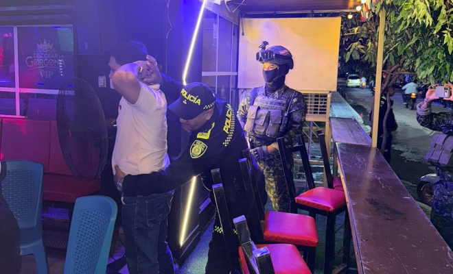 Dos funcionarios policiales realizando registro a persona a un ciudadano en establecimiento abierto al publico 