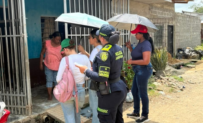 Funcionaria policial en compañía de tres funcionarias del ICBF en actividad puerta a puerta junto a una ciudadana