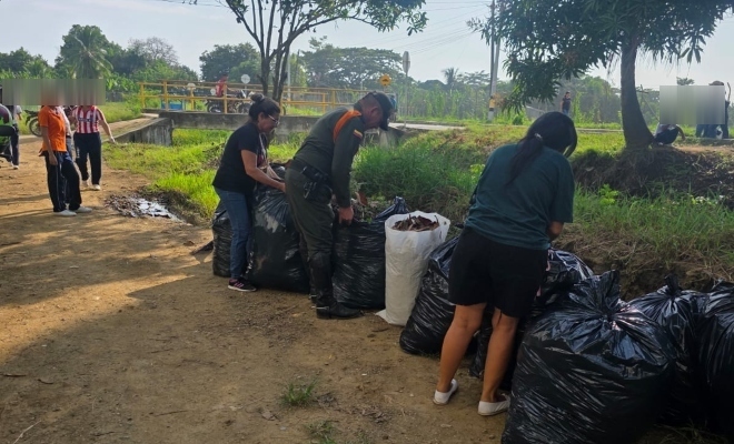 Funcionario policial realizando actividad de limpieza y recuperaci&oacute;n de espacios junto a dos ciudadanas 