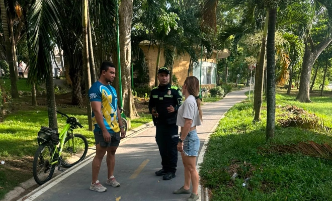 Funcionario policial brindando recomendaciones de seguridad a dos ciudadanos en el parque ronda del Sinú 