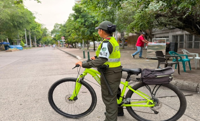 una  funcionaria  de la policía nacional  en un bicicleta  sobre la vía avenida primera   