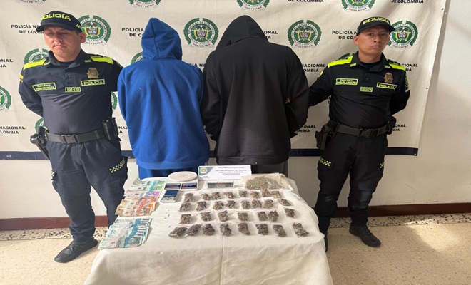 Policias con personas capturadas y en la mesa estupefacientes incautados 