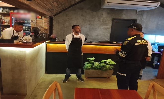 un uniformado con un ciudadano  en un establecimiento abierto al publico brindando recomendaciones  