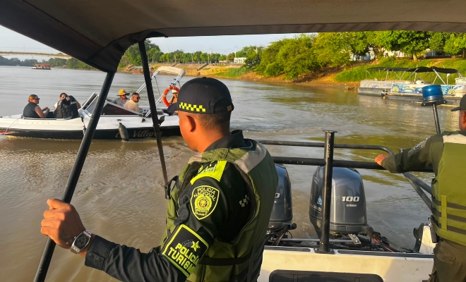 Funcionario policial en embarcación realizando recorrido por el rio Sinú donde se observa a un grupo de ciudadanos en otra embarcación 