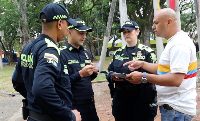 tres policias y una persona con la camiseta de colombia mirando el album
