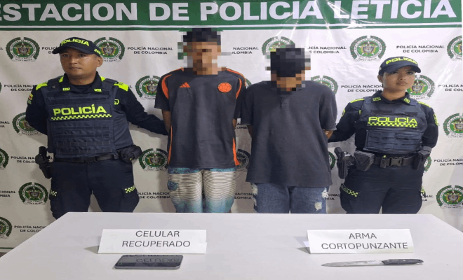 En el lugar se encuentran dos policías y dos personas frente a ellos hay una mesa sobre la cual reposan un celular y un arma cortopunzante tipo cuchillo