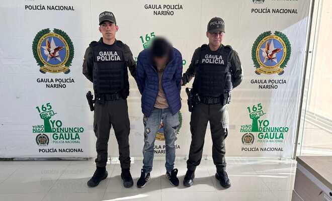 Una persona capturada esposada con dos policias del GAULA a sus lados respectivamente 