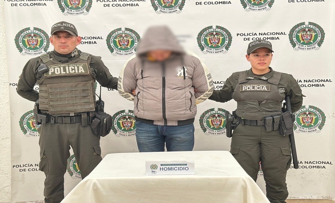 Un ciudadano esposado, capturado con dos uniformados en cada lado respectivamente 