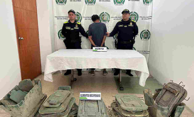 Hombre capturado en medio de dos polic&iacute;as, en frente elementos incautados