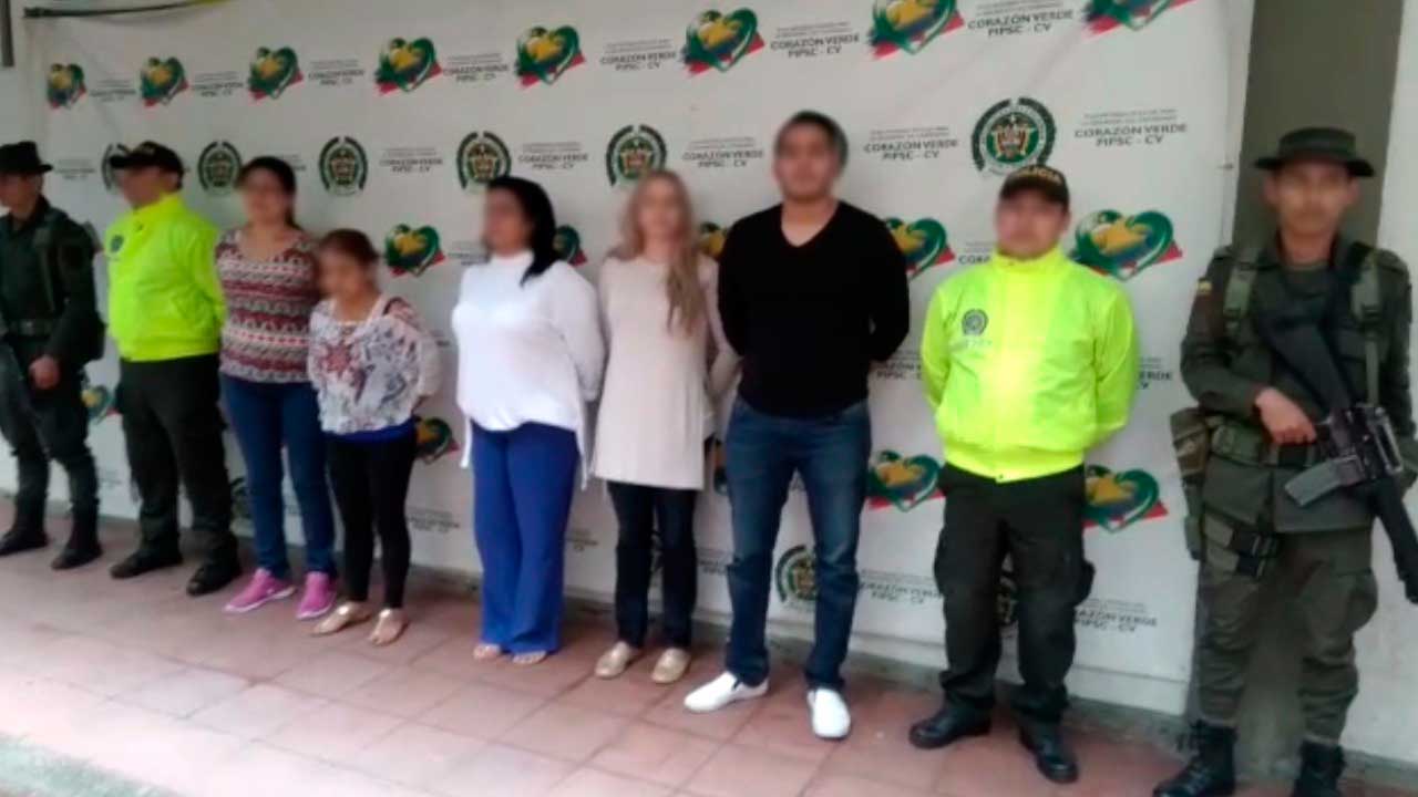 fotografía mostrando seis personas capturadas, con policias a los lados