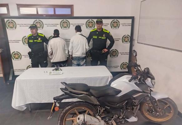 Dos hombres capturados en medio de dos policías, con arma de fuego y una motocicleta incautada