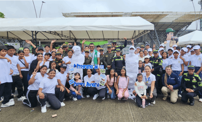 Un grupo de diez polic&iacute;as est&aacute; de pie acompa&ntilde;ados a ambos lados por ni&ntilde;os y ni&ntilde;as vestidos con camisas blancas todos se encuentran formados al centro destaca un marco azul y al fondo se observa una carpa blanca