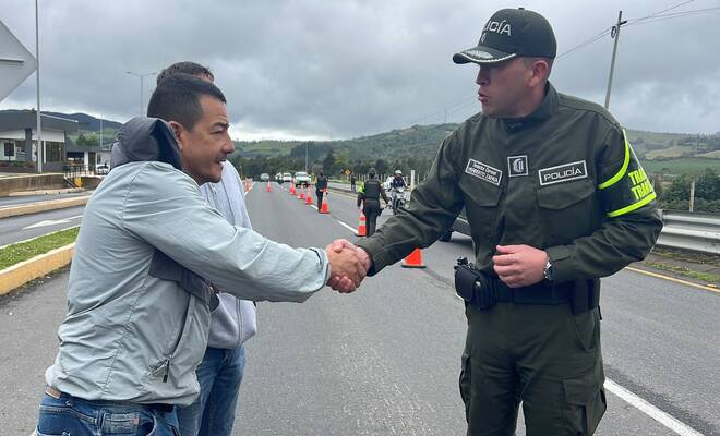 Un uniformado d ela Polic&iacute;a dando la mano a dos ciudadanos en la v&iacute;a 