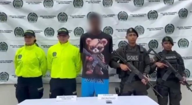 cuatro polic&iacute;as al lado de un hombre capturado con material incautado