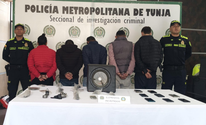 5 personas capturadas, en cada lado un polic&iacute;a y en la mesa elementos incautados