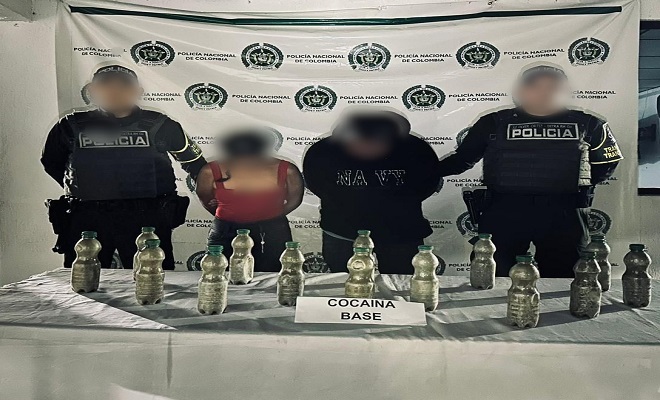 Dos Policías de Tránsito junto a un hombre y una mujer capturados con elementos incautados sobre una mesa 