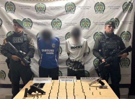la policía nacional al lado de dos hombres capturados con arma de fuego y municiones 