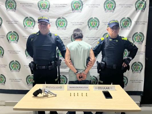dos policías al lado de un hombre capturado por porte ilegal arma de fuego 