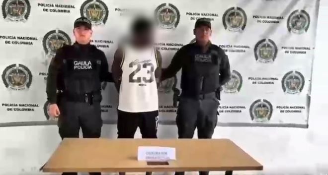 dos policías al lado de un hombre capturado por extorsión