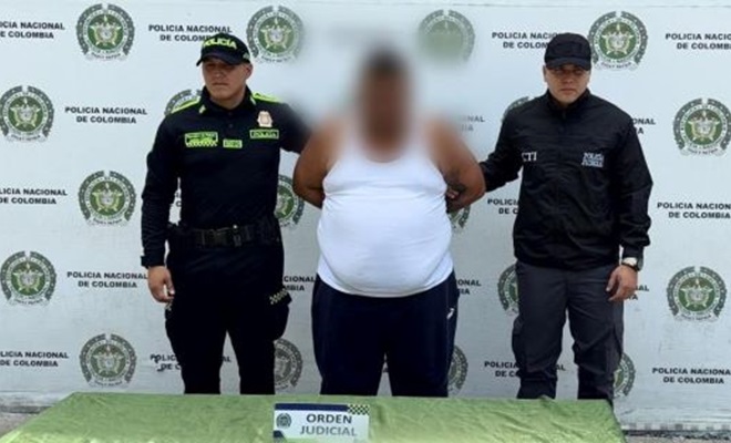 Dos polic&iacute;as al lado de un hombre capturado por orden judicial 
