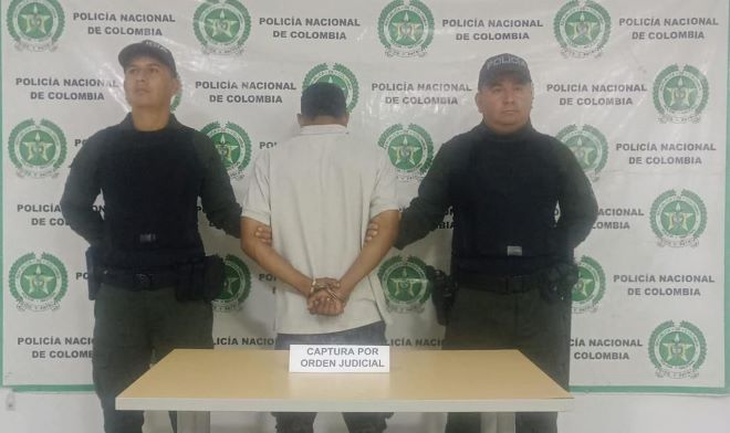 dos policías al lado de un hombre capturado por orden judicial