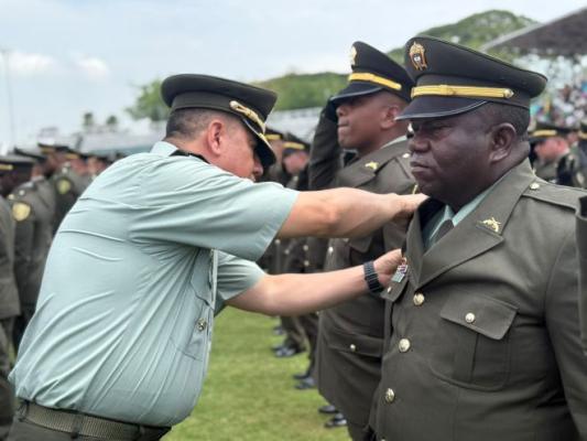 el se&ntilde;or coronel al lado de un polic&iacute;a colocando la insignia