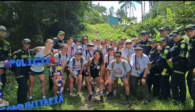 Una amplia agrupaci&oacute;n de personas se posa en un entorno con vegetaci&oacute;n al fondo, mezclando deportistas y miembros de la fuerza policial. Todos est&aacute;n juntos, formando un solo grupo en una foto colectiva que une al equipo deportivo con la instituci&oacute;n policial, mostrando una relaci&oacute;n de colaboraci&oacute;n o evento conjunto