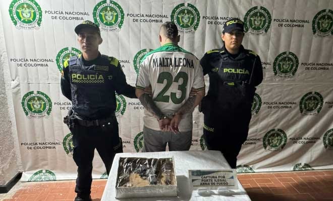 Hombre capturado en medio de dos Policías, en frente armas de fuego incautadas