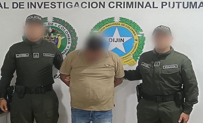 Policías presentan a sujeto capturado frente a una pared con escudo institucional 