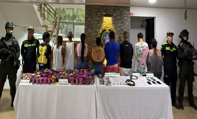 Cinco celulares, dinero en efectivo, marihuana y cocaína incautados sobre una mesa, junto con nueve capturados y cuatro policías