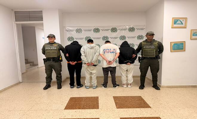 Cuatro personas capturadas, las cuales se encuentran esposadas con dos policías en cada lado respectivamente 