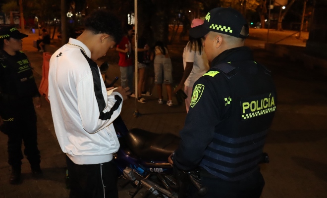 hombre con chaqueta blanca, motocicleta y policías revisando documentos