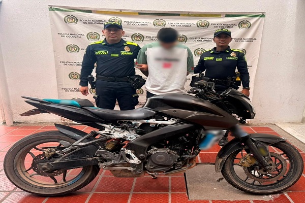 Dos policías junto a un hombre capturado y una motocicleta recuperada